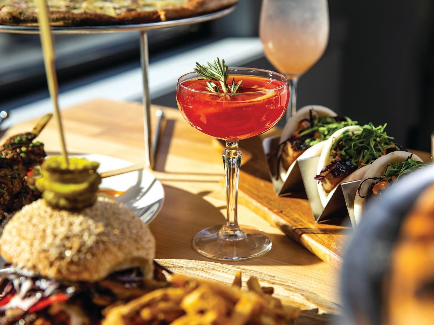 A variety of plates from Stove and Tap surround one of its specialty cocktails. PHOTO BY EDDY MARENCO